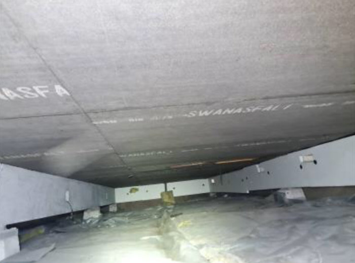 Undersidan av en bjälklag med synliga isoleringsplattor och påskrift.