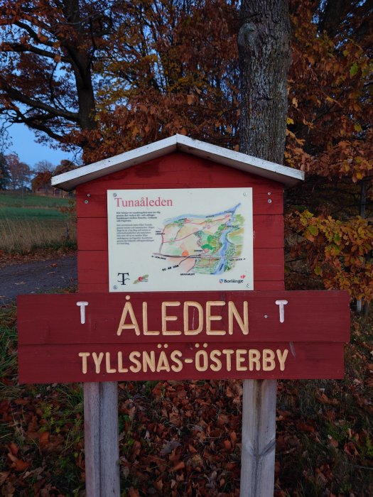 Informationsskylt för Tunaåleden med karta och riktning mot Tyllsnäs-Österby mot höstlig bakgrund.