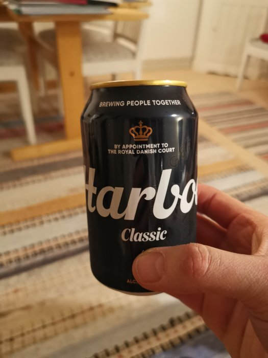 Hand håller en Carlsberg ölburk med texten "By Appointment to the Royal Danish Court".