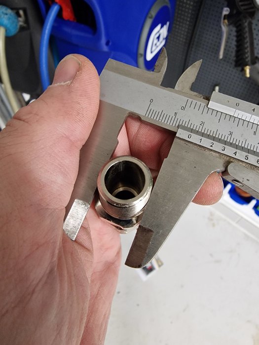 Hand håller ett skjutmått som mäter diametern på en metallrörsände.