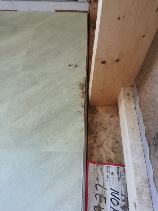 Reglar för en bärande vägg under golvspånet där en mätsticka syns vid skarven mellan vägg och golv.