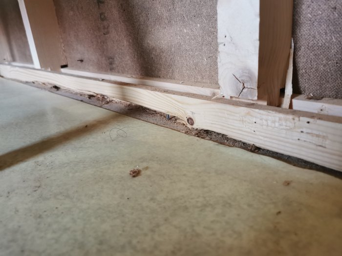 Närbild av väggens nederdel där reglarna är dolda under golvspånet.