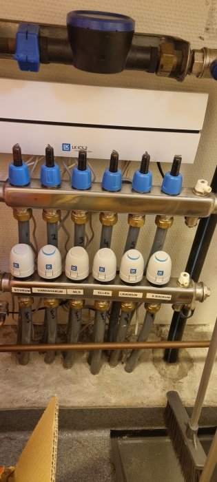 Installation av LK golvvärmefördelare med märkta ventiler för olika rum.