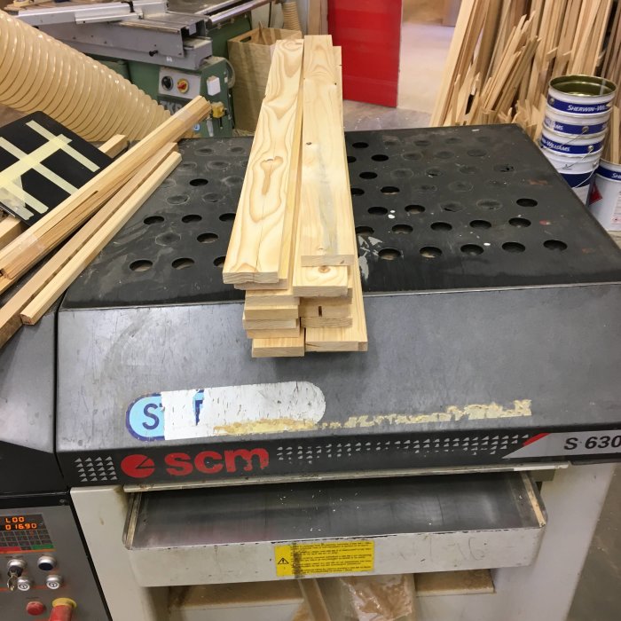 Nyhyvlade lådsidor och lådbakstycken av gran placerade på industrisnickarmaskin.