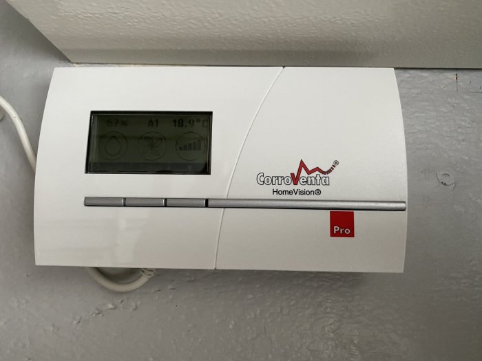 Väggmonterad CorroVenta HomeVision Pro kontrollpanel för ventilation med display och knappar.