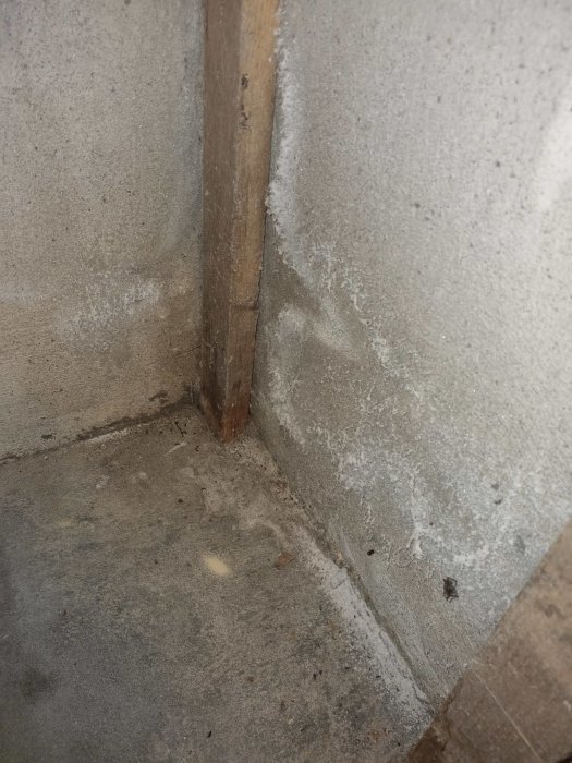 Saltpåverkat hörn där betonggolv möter vägg med synlig fukt och saltavlagringar.