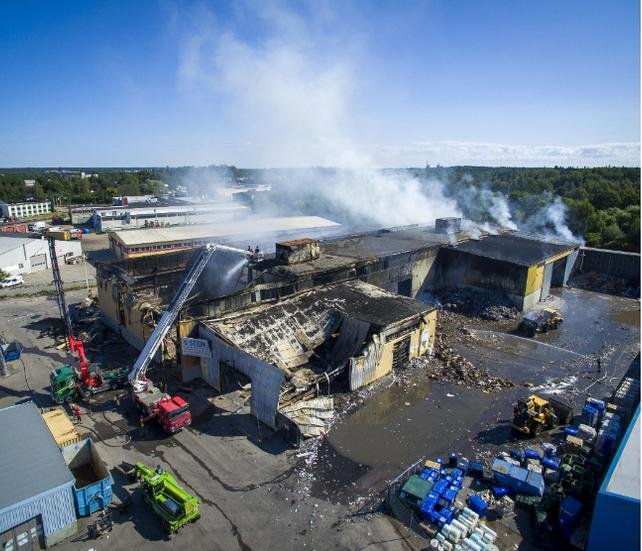 Luftvy av brandskador på Stenas pappersåtervinningsanläggning med släckningsarbete pågående.