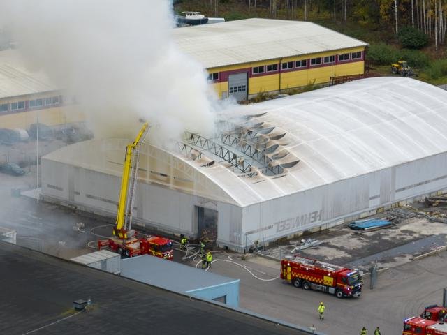 Brandmän släcker en brand på Stenas pappersåtervinningsanläggning under ett stort vitt tält.