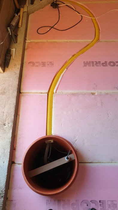 Pumpgrop med nivåvakt och värmekabel i en snickarverkstad, omgiven av cellplastisolering.