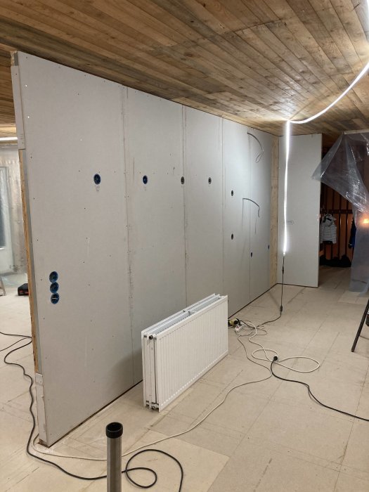 Gipsade väggar i byggprocess med ett fristående element i ett garage under renovering.