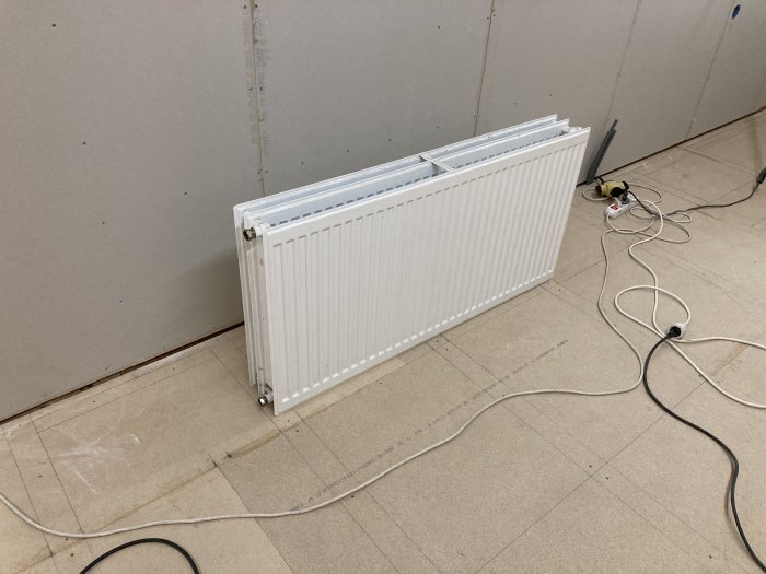 Element står mot vägg med gipsplattor under renovering, elsladdar på golvet.