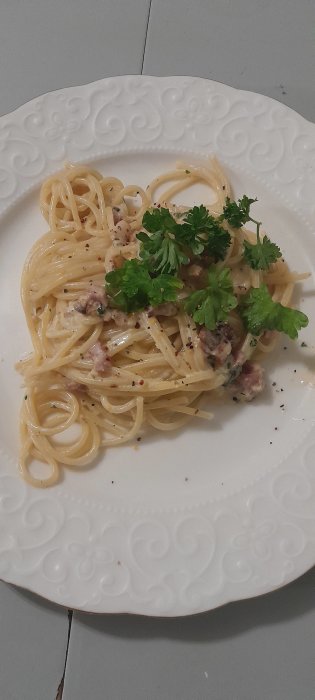 Tallrik med spaghetti carbonara toppad med färsk persilja.