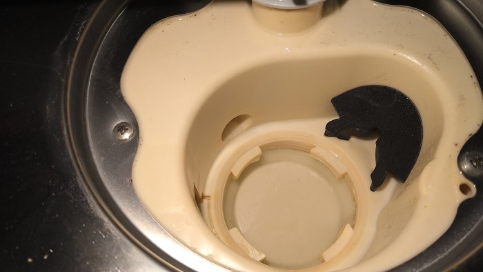 Våt och smutsig diskho med vattenansamling, frigolitflottör och en geting. Potentiell läcka synlig.