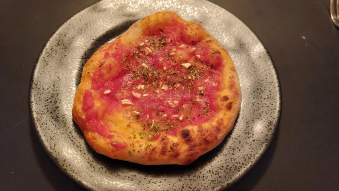 Hembakad pizza Marinara med tomatsås och hackad vitlök på en keramisk tallrik.