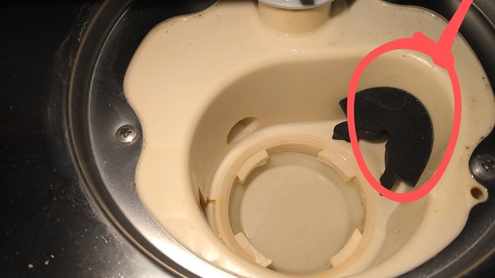 Vattenläcka från en gummislang med rostig slangklämma i en diskho, markerad vid klockan 1 position.