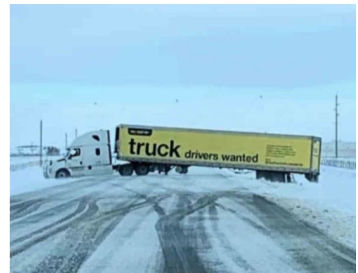 Lastbil med texten "truck drivers wanted" har kört av vägen på ett snötäckt landskap.