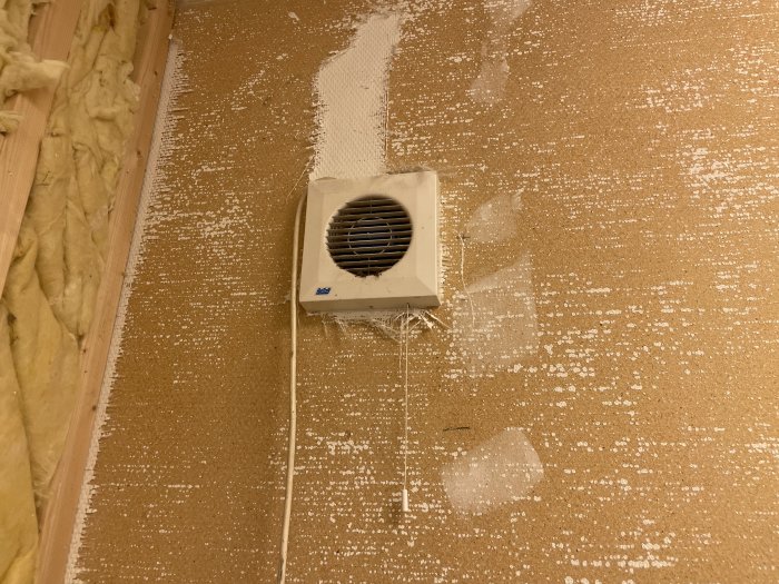 Ventilationsgaller på en isolerad vägg med synliga spackelrester under renovering.