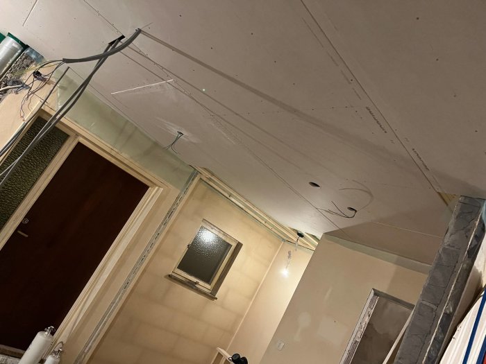 Nyinstallerat undertak i rum under konstruktion, synliga ledningar och ej färdiga väggar.
