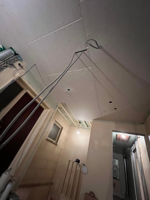 Delvis färdigställt undertak med synliga elledningar och oisolerat ventilationsrör i ett pågående renoveringsprojekt.