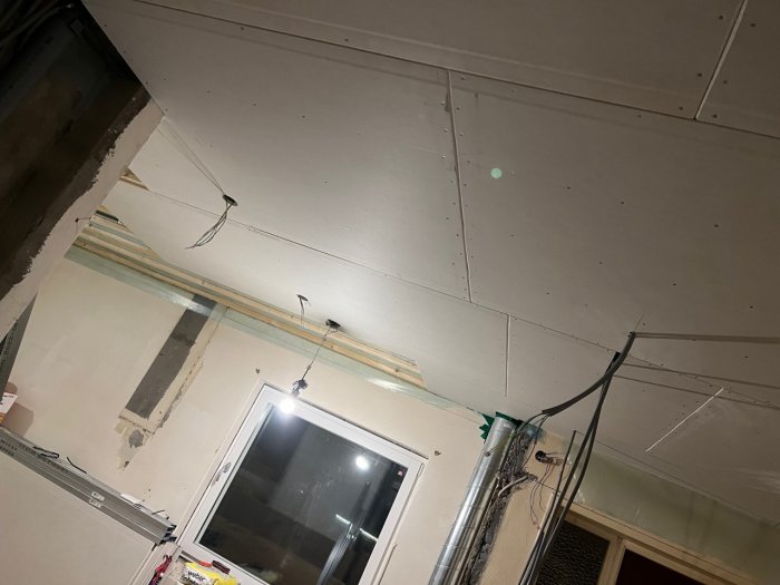 Nyinstallerat undertak med synliga elkablar och ofärdig vägg vid ventilationsrör.
