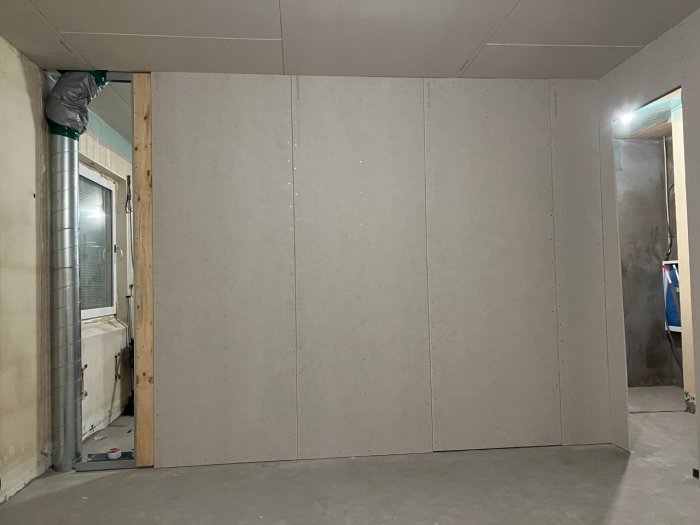 Nyuppsatta gipsskivor på vägg i ett pågående renoveringsprojekt, med synligt ventilationsrör.