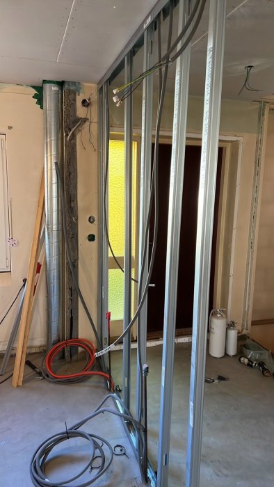 Renovering med öppna väggstommar och elinstallation, dragning av el-, signal- och patchkabel på golvet.