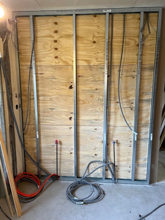 Köksvägg under renovering med dragning av el- och kommunikationskablar mot träskivor och stålreglar.