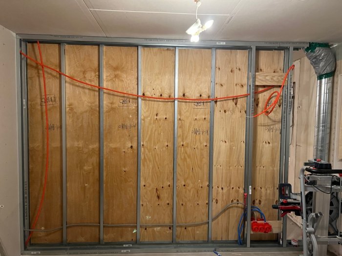 Köksvägg under renovering med öppen stomme och framdragna el- och signal-/patchkablar.