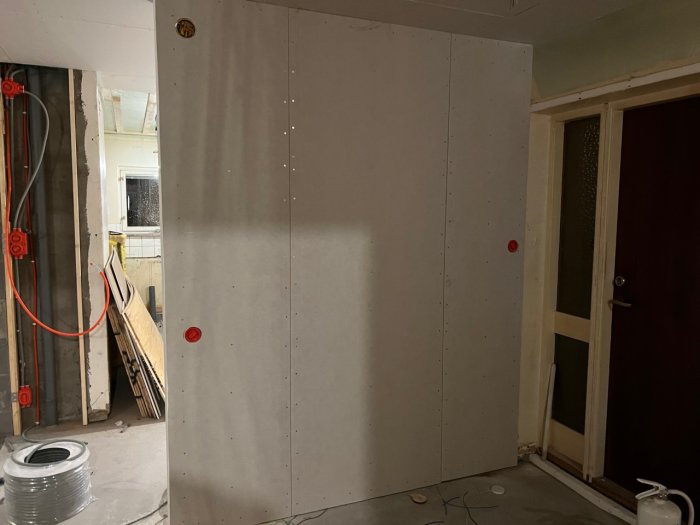 Gipsvägg med elinstallation, kabelspolar och genomföringar för el i underrenoverat kök.