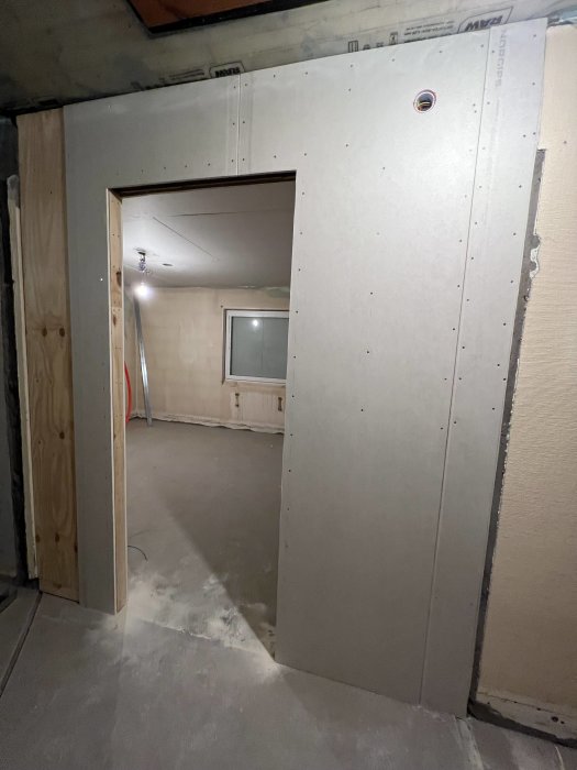 Nyinstallerade gipsskivor i korridor med tätning runt kanter och ett dörrhål, redo för ljuddämpning.