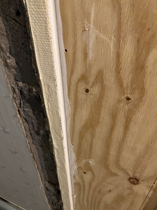 Närplan av en väggunderkonstruktion visande tätning vid en träregel intill en betongvägg.
