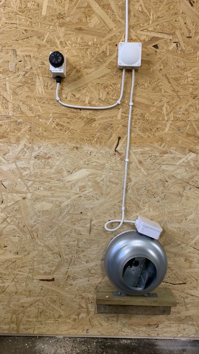 Installerad värmare med anslutna kablar och timer på en OSB-vägg i ett byggprojekt.