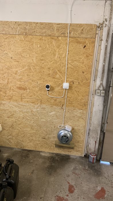 Nyinstallerad värmare med elektriska ledningar på en OSB-vägg i ett garage.