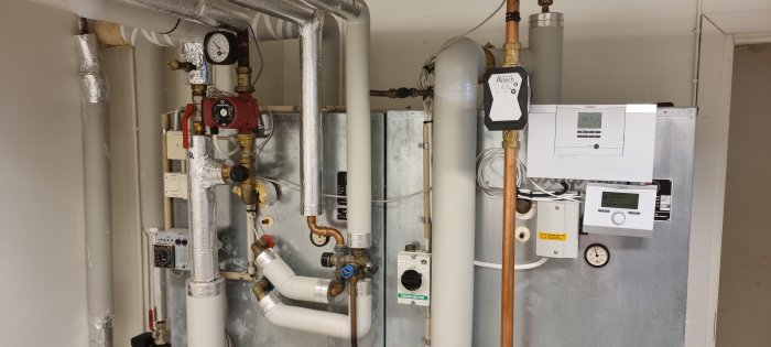 Värmesystem med rör, mätare och Altech pump, samt inflöde och temperaturvisare synliga.