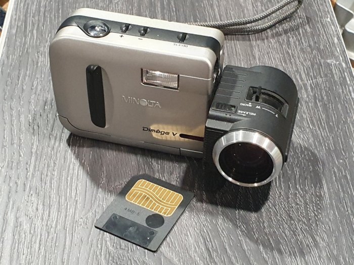En gammal Minolta Dimage V digitalkamera från 1998 bredvid ett 4 MB minneskort på ett bord.