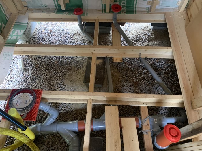 Bild av en träbjälklagkonstruktion med rörinstallationer och grusunderlag.