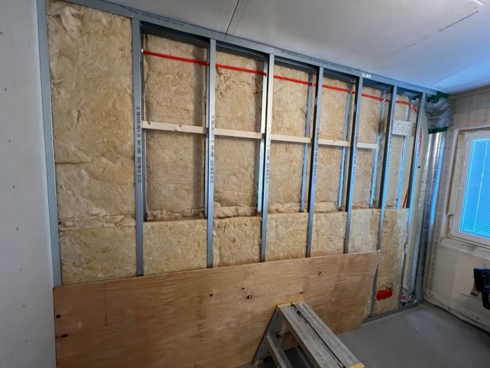 Isolerad väggstomme med mineralull, plywood och ventilationsrör före slutskepp av vägg.