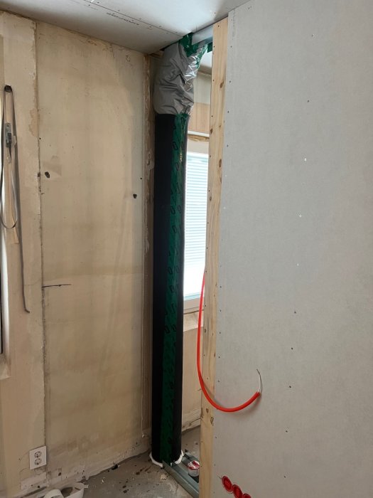 Renoveringsarbete med väggisolering och avloppsrör, plywood och osäkra gipsväggar vid ett byggprojekt.