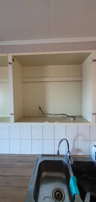 Överskåp utan dörrar över diskho med synlig elinstallation och hyllplan.