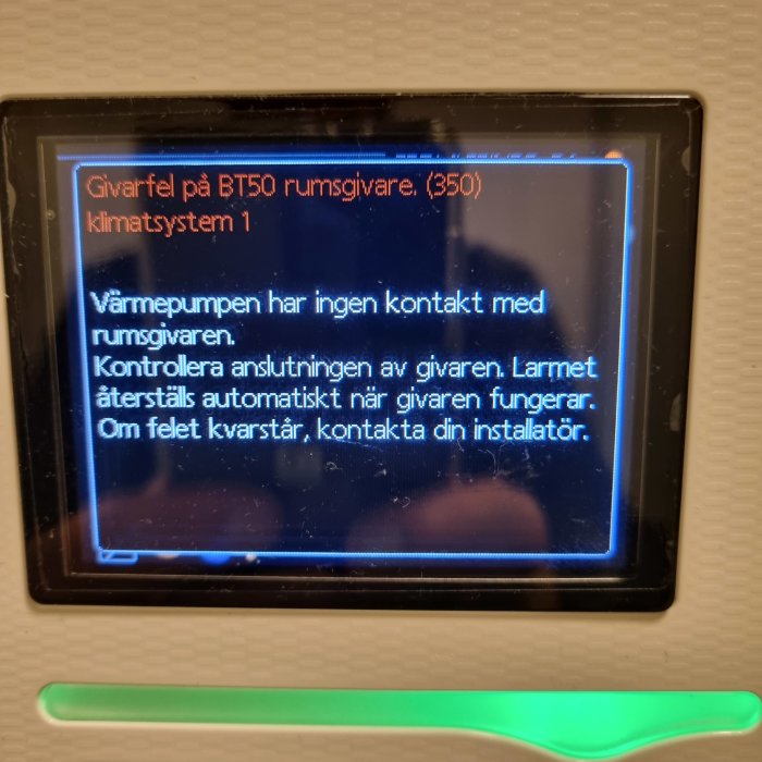 Digital kontrollpanel som visar ett felmeddelande om avsaknad kontakt med rums-givaren för en värmepump.