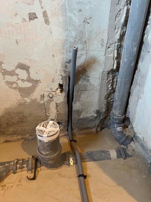 Installationsarbete för golvvärme med synliga rör och spår i betonggolvet i ett under renovering badrum.
