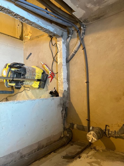 Installation av golvvärmeslang i badrum med synliga rör och verktyg på betonggolv.