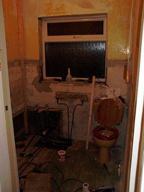 Renoveringsprojekt av badrum med demonterat badkar, exponerade rör och delvis borttagen väggklädsel.