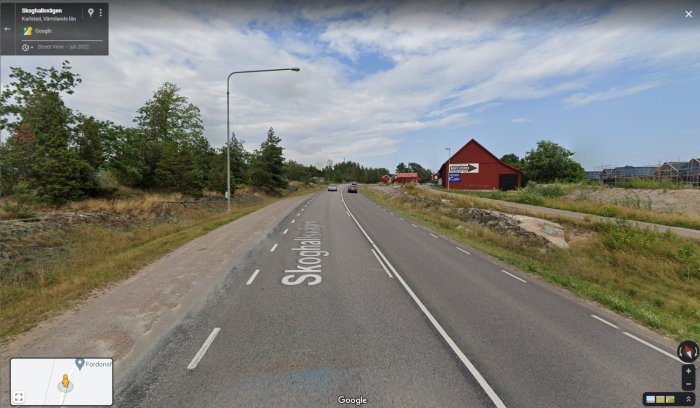 Landsväg vid Skoghall med körbanor, trafik och en röd lada i bakgrunden; ingen synlig cykelbana.
