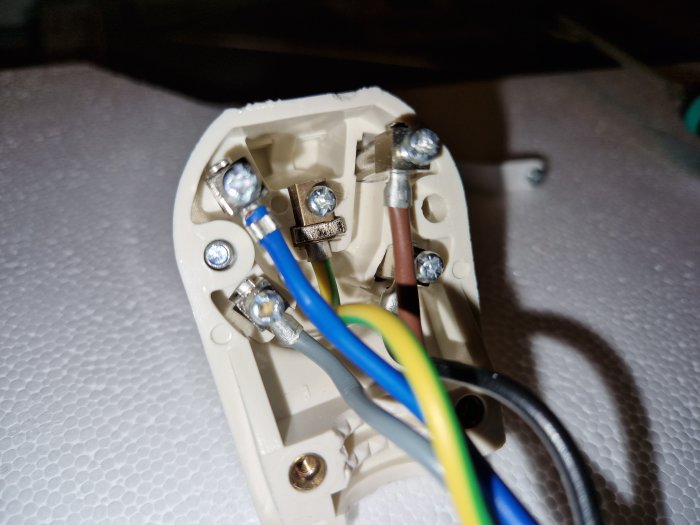 Eluttagets insida, anslutna kablar, skruvanslutningar synliga, installationsarbete, elförsörjning, närbild, elektrisk säkerhet.