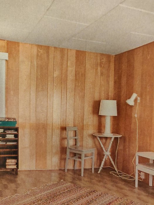 Retro rum med träväggpanel, vita möbler, golvbelysning, vävda mattor och en hylla med böcker.