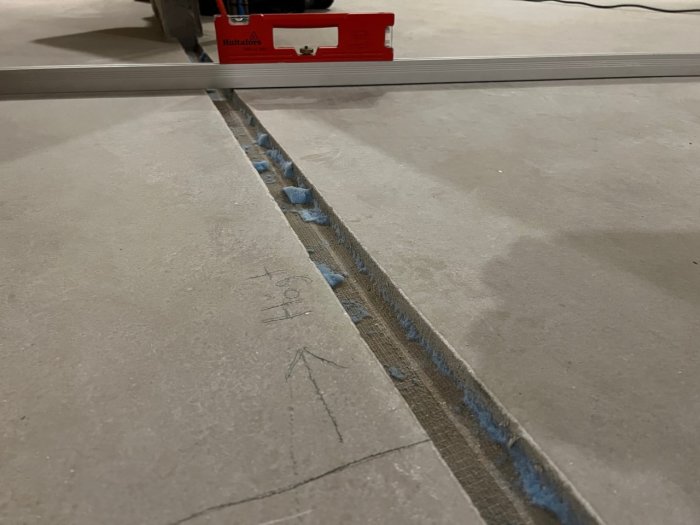 Byggarbetsplats med vattenpass, betonggolv och markeringsband för eventuell konstruktion eller renovering.