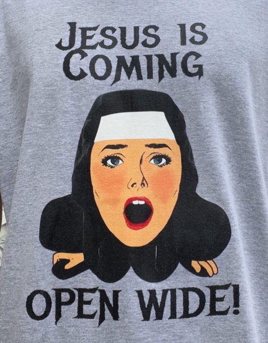 Grå t-shirt med tryck, karikatyr av nunnfigur, text "Jesus is coming, open wide!".