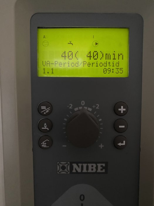 Digital termostat med LCD-skärm visar temperatur och tid, kontrollknappar nedanför, märkt "NIBE".