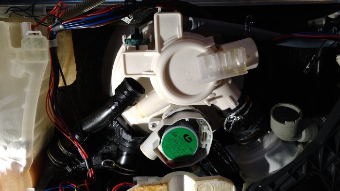 Bild på fordonets motorutrymme, fokus på en plastkomponent, kablar och anslutningar synliga, komplex maskinell uppbyggnad.